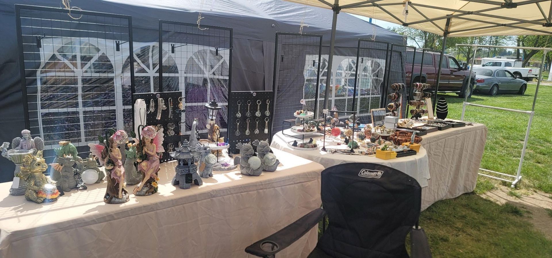 Outdoor market stall displaying decorative ceramics on tables under a canopy.
