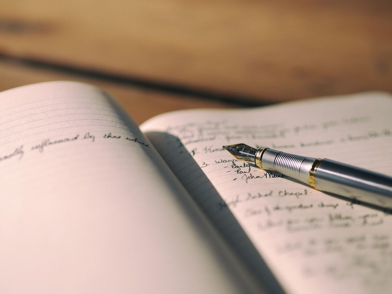 Picture of a notebook with something written on it, with an ink pen on top of it