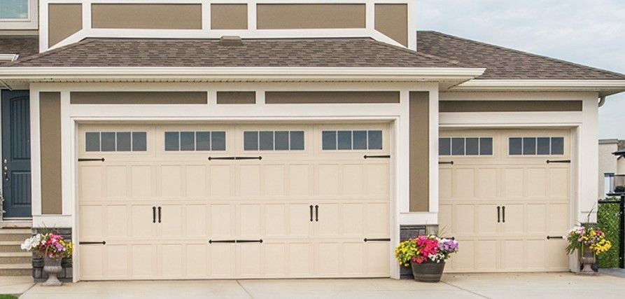 A large house with two garage doors in Palmetto Ga and flowers in front of it.