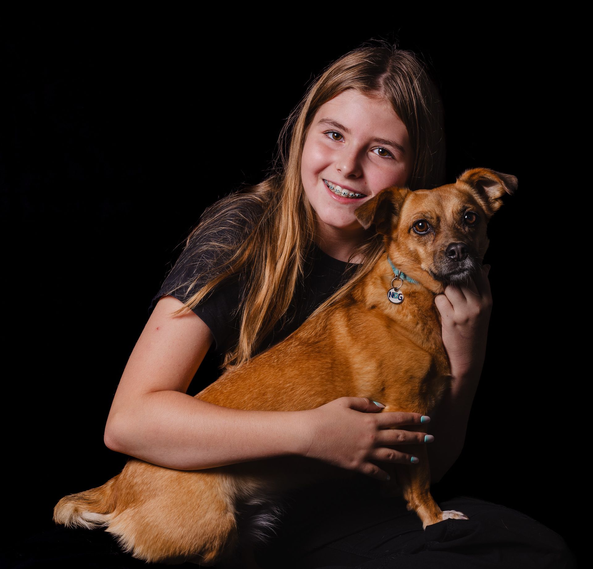 Een jong meisje houdt een kleine bruine hond in haar armen.