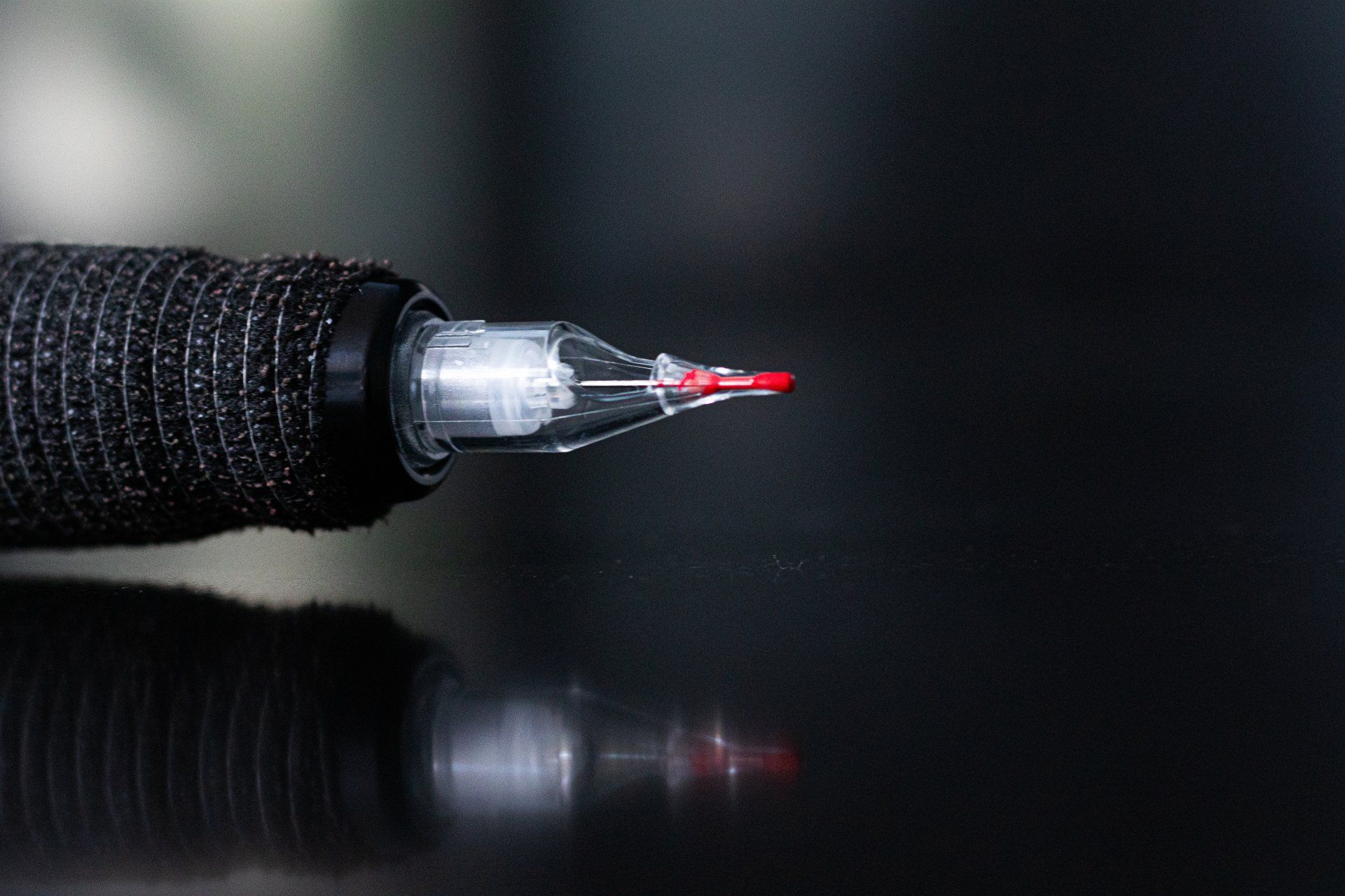 Een close-up van een tattoo-machine met een rode naald.