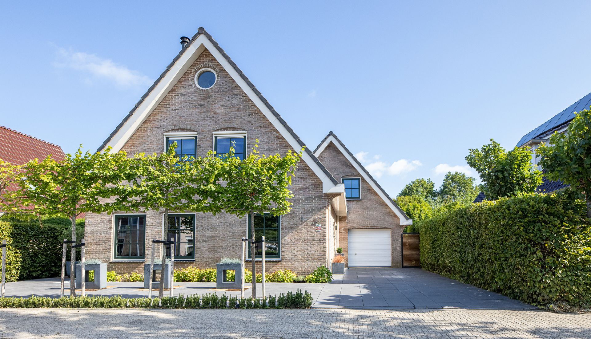 Een groot bakstenen huis met een garage en een oprit