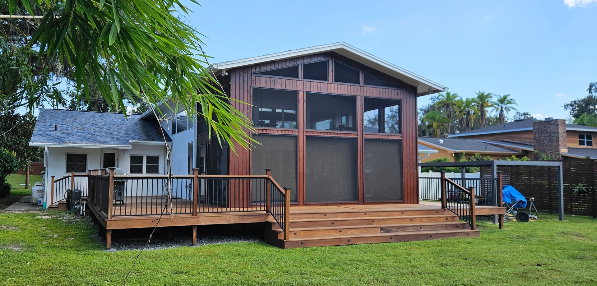 Two small wooden cabins on a grassy lot, one with a porch and one with a screened front