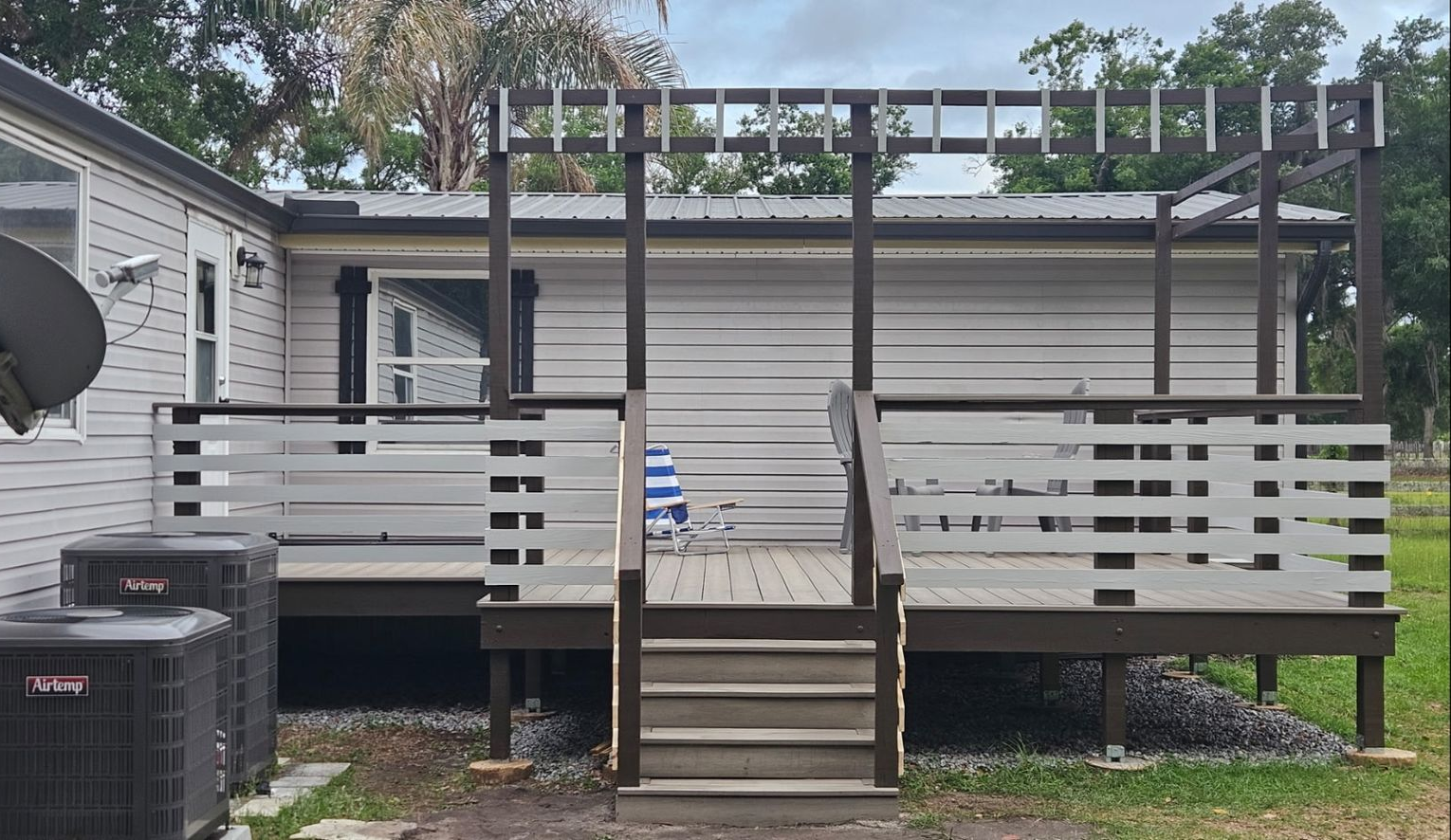 Backyard deck with stairs, white railing, and pergola beside a house