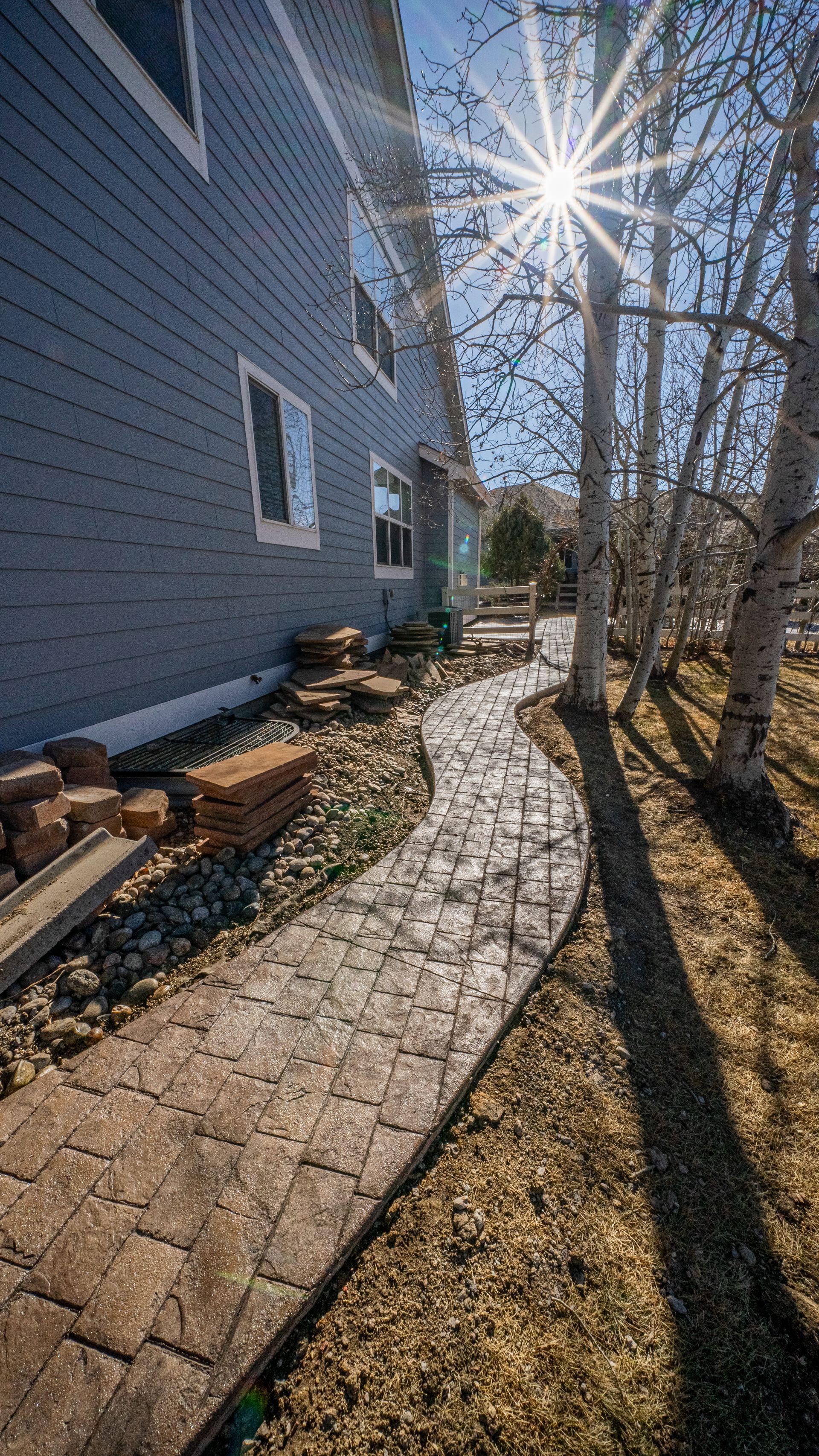 A concrete walkway leading to a house with a lush green lawn.