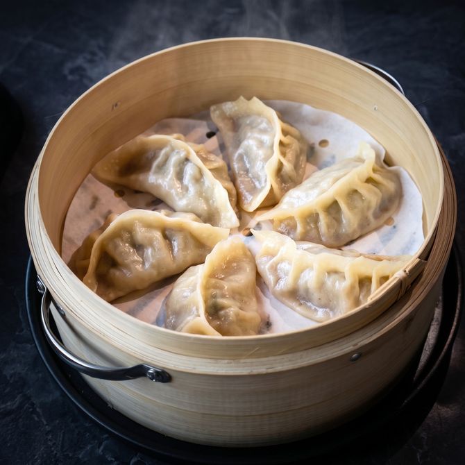 Steamed dumplings in a bamboo basket on a dark background