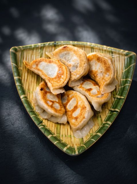Green leaf-shaped plate with sliced dumplings or pastries on a dark background