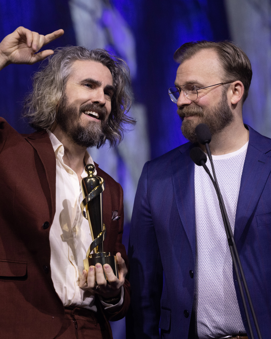 Two men are standing next to each other and one is holding an oscar statue.