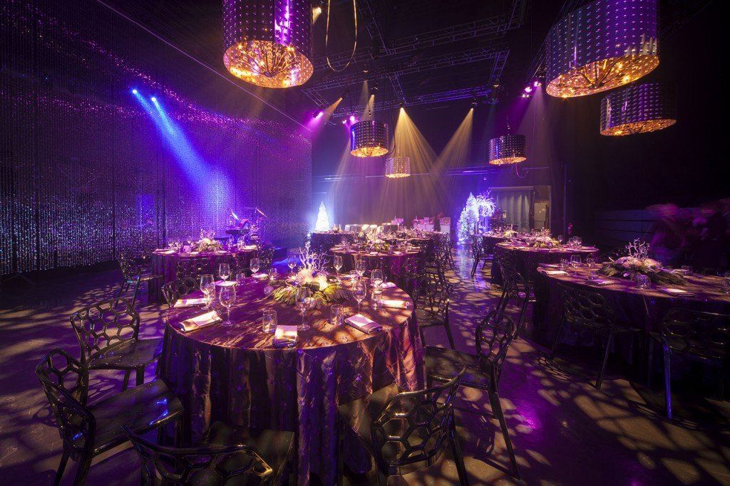 A large room filled with tables and chairs and purple lights.