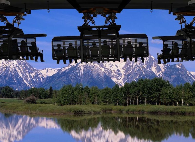 A group of people are riding a ferris wheel with mountains in the background