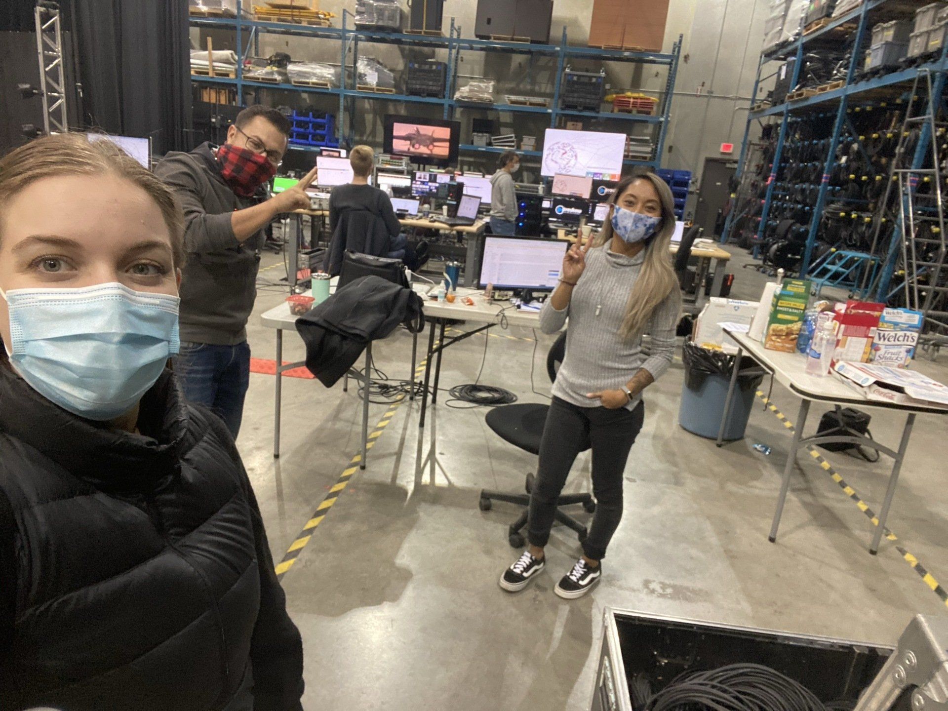 A man and a woman wearing face masks are standing in a warehouse.