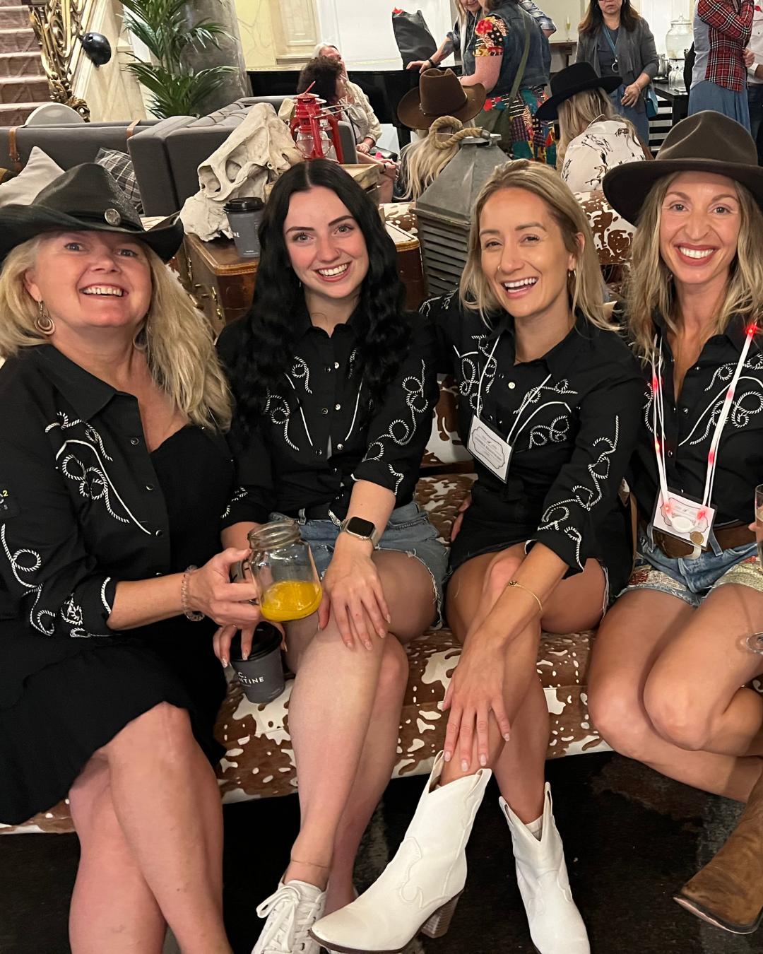 A group of women wearing cowboy hats are sitting on a couch.