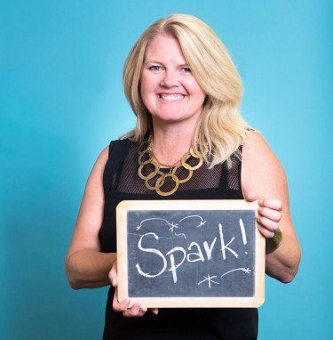 A woman is holding a sign that says spark