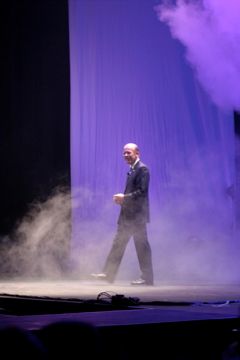 A man in a suit is walking on a stage with smoke coming out of it.