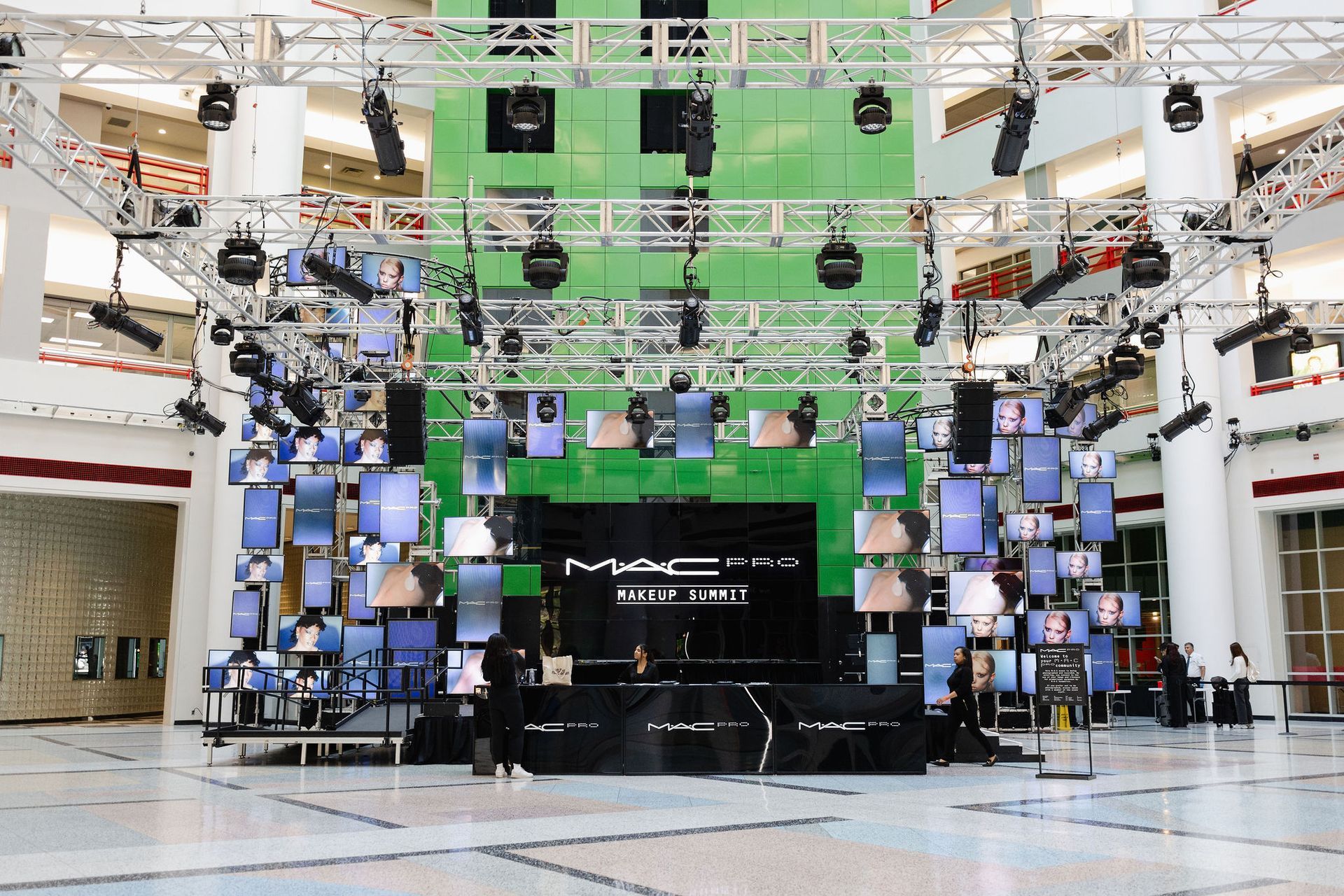 MAC Cosmetics stage setup: screens, lights, and products in a large atrium.
