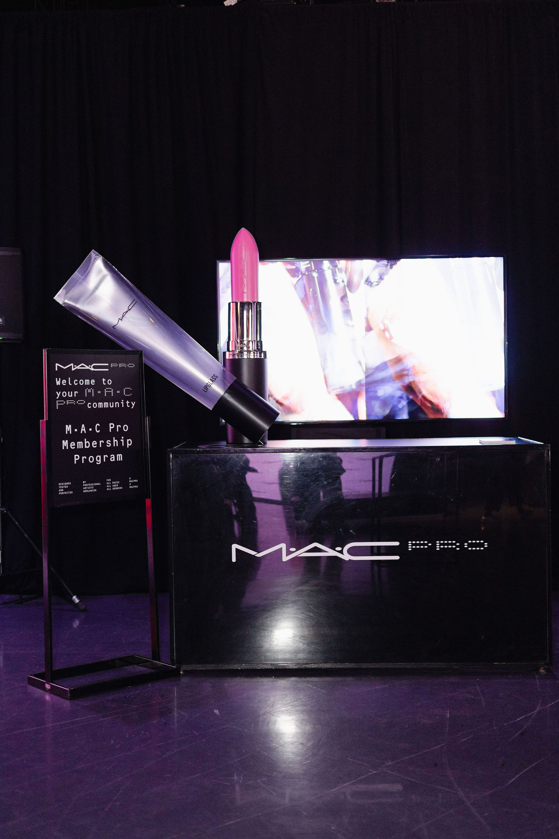 MAC cosmetics display with lipstick, gloss, and a monitor screen.