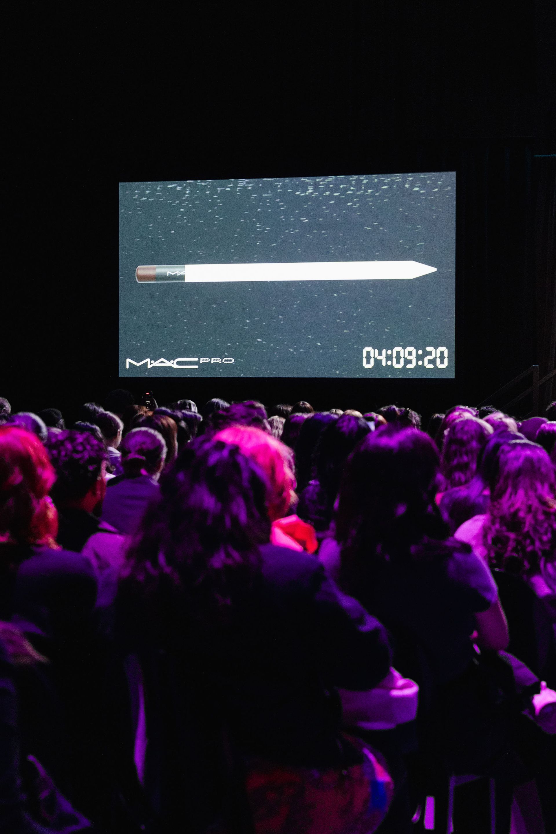 Audience watches a screen showing a MAC product against a starry background, timer reads 04:09:20.