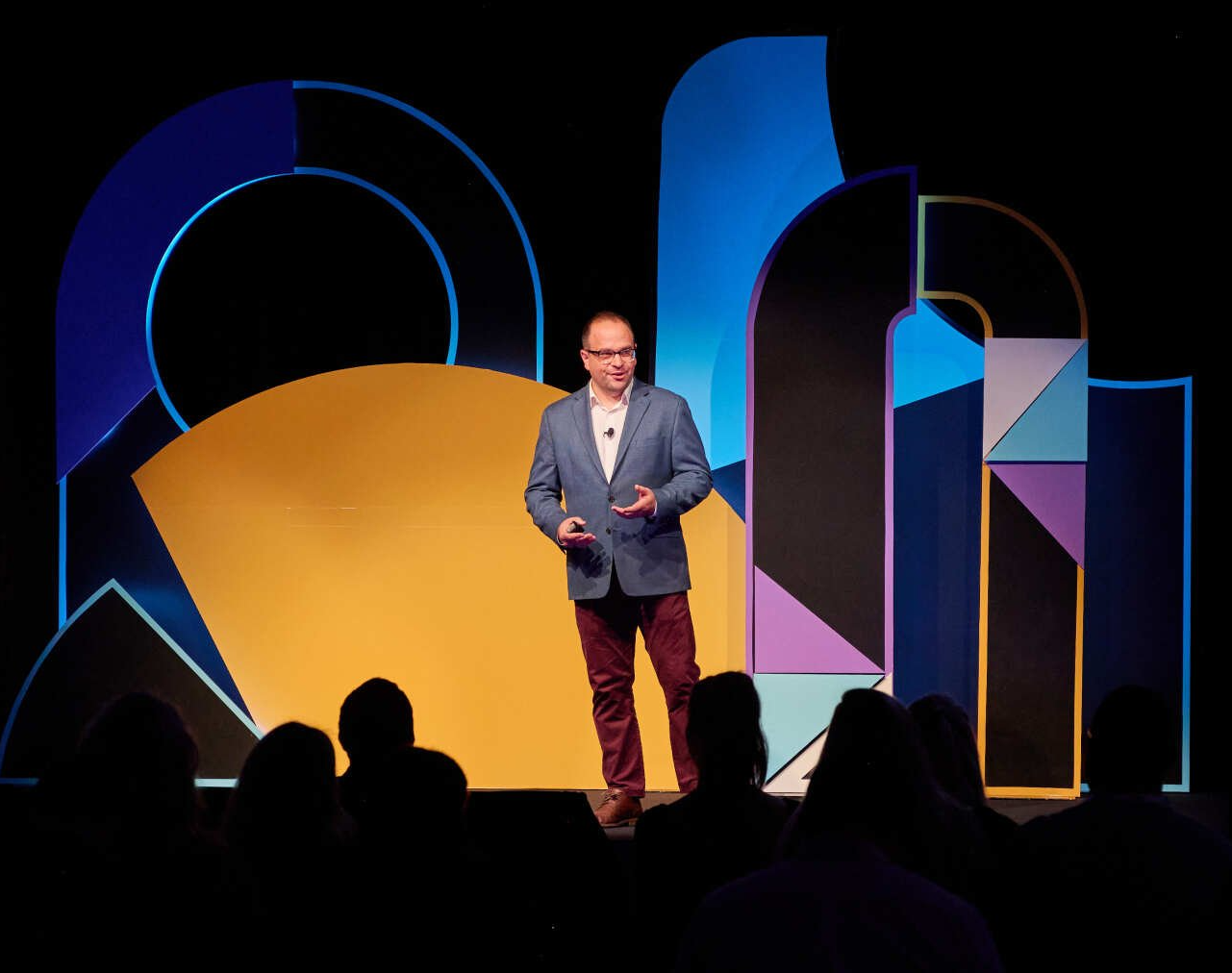 A man is giving a speech on a stage in front of a crowd