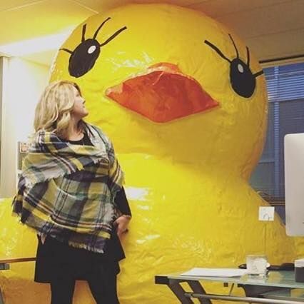 A woman standing next to a giant yellow duck