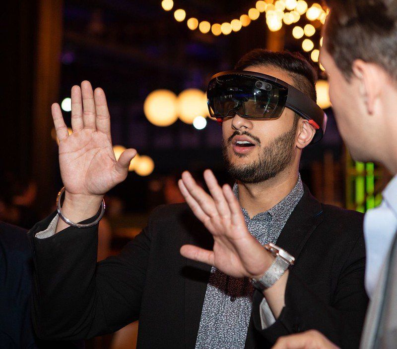 A man wearing a virtual reality headset is talking to another man.