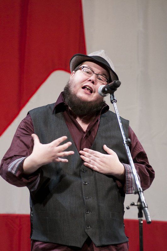 A man with a beard is singing into a microphone