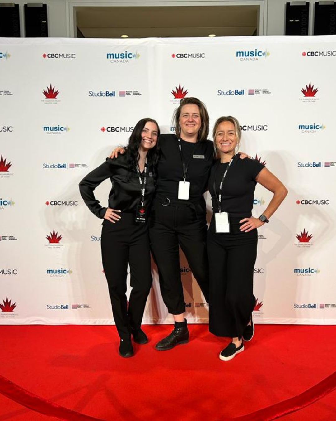 Three women are posing for a picture on a red carpet.