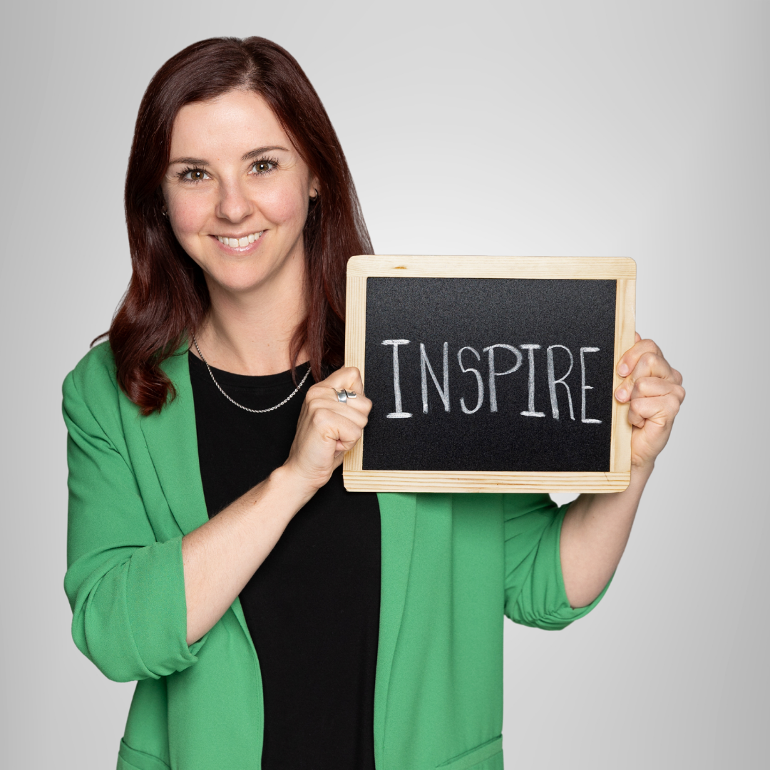 A woman in a green jacket is holding a sign that says inspire