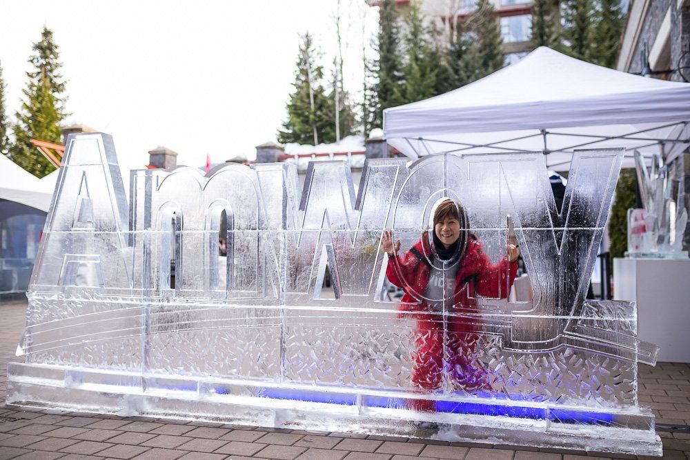 A woman is standing in front of a large ice sculpture.