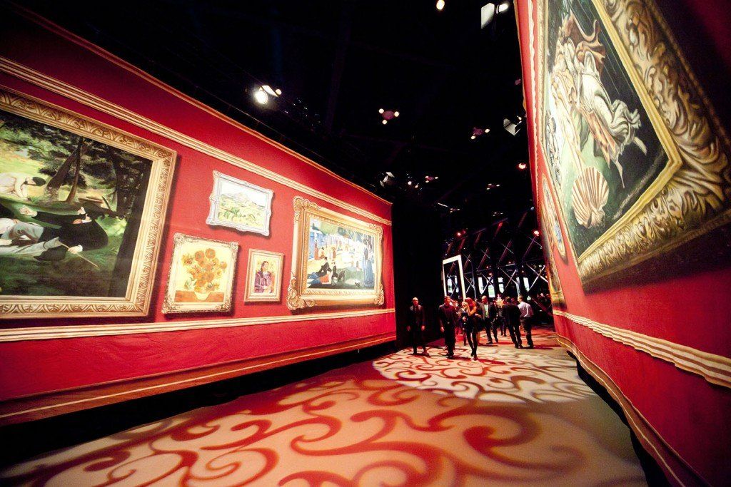 A group of people are looking at paintings in a museum