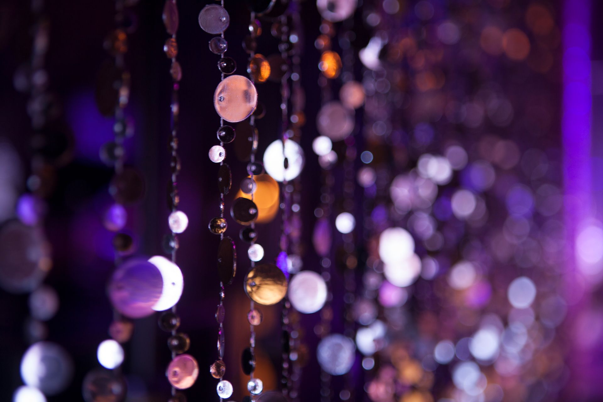 A close up of a string of beads with purple lights in the background.