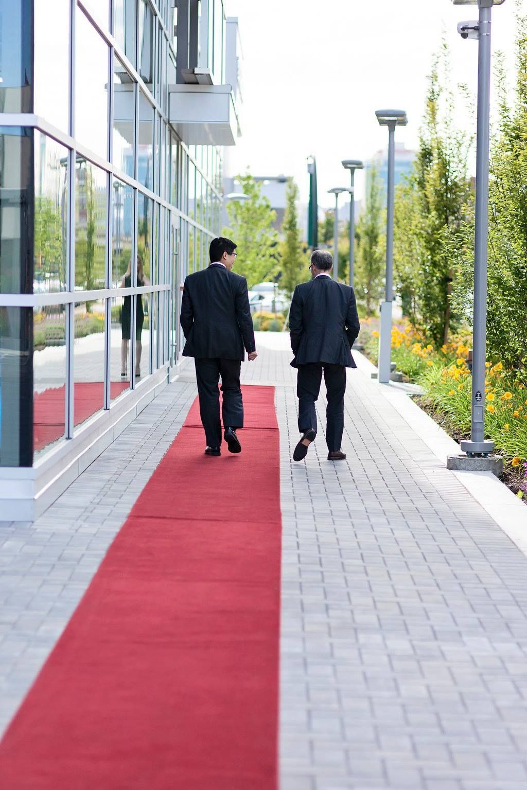 Two men in suits are walking down a red carpet