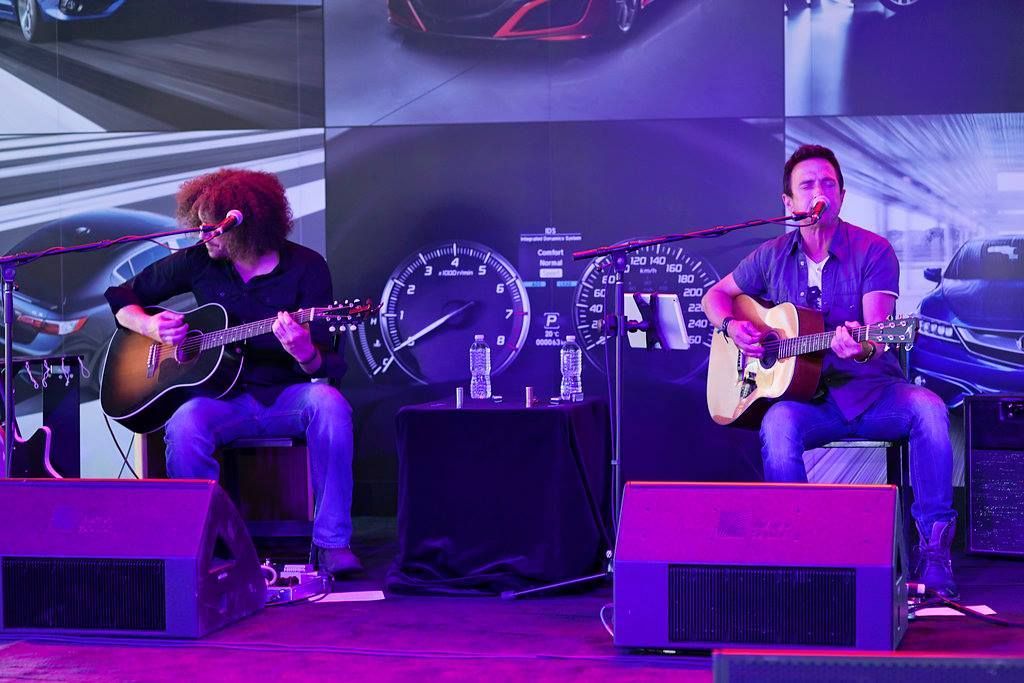 Two men are playing guitars and singing into microphones on a stage.