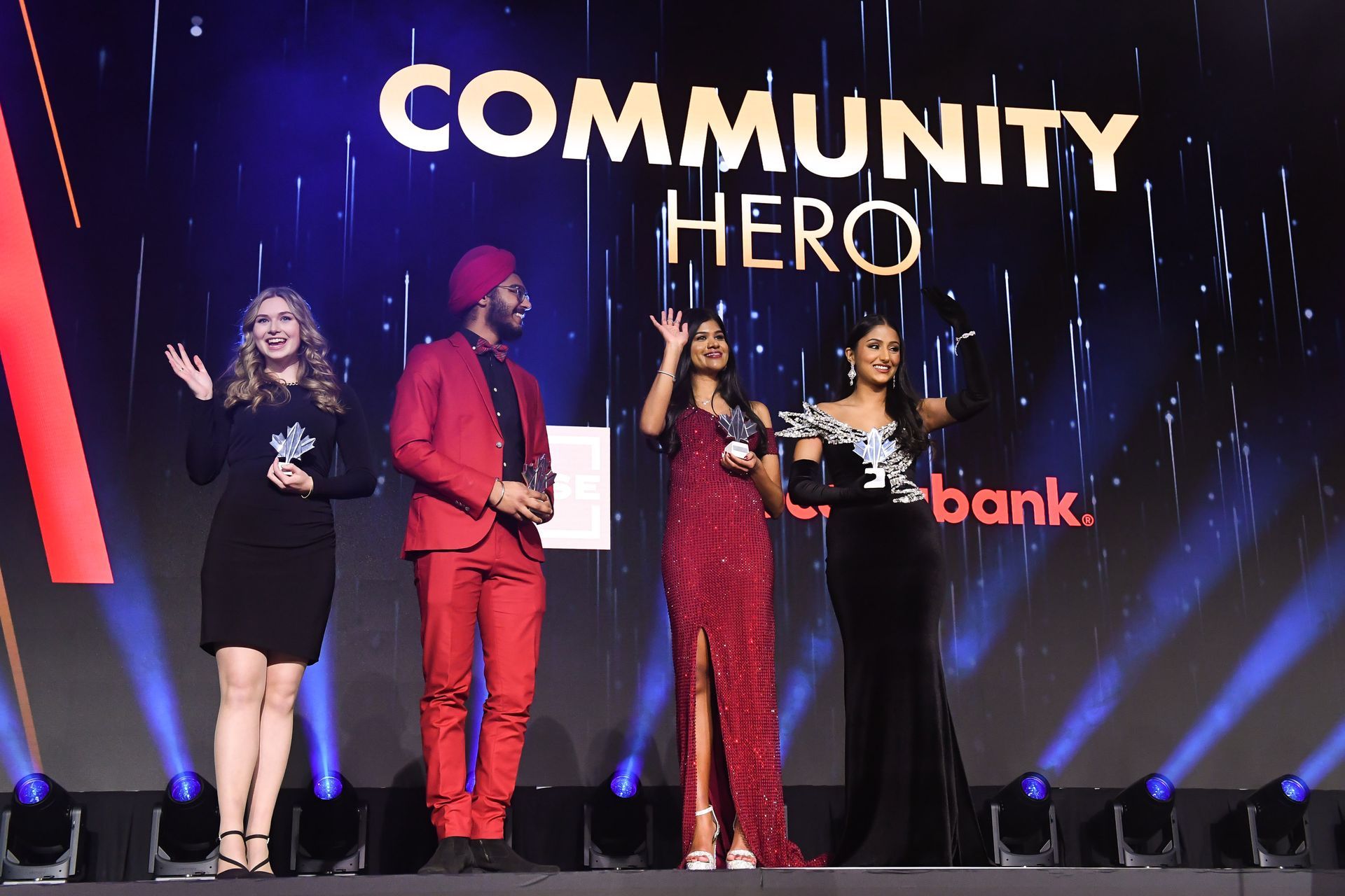 A group of people are standing on a stage at a community hero event.