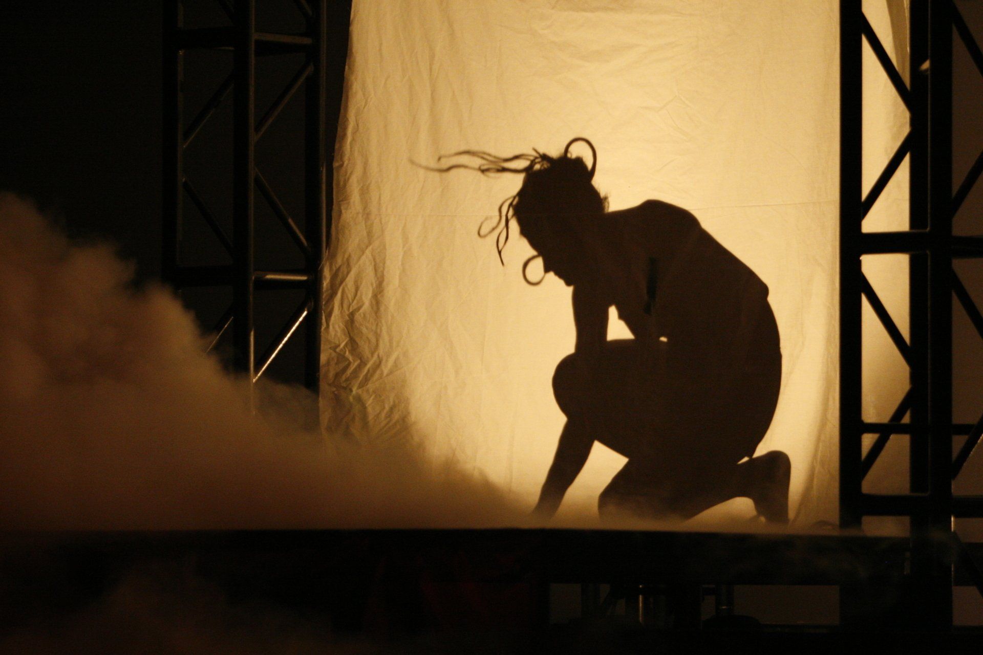 A shadow of a woman kneeling down with her head down