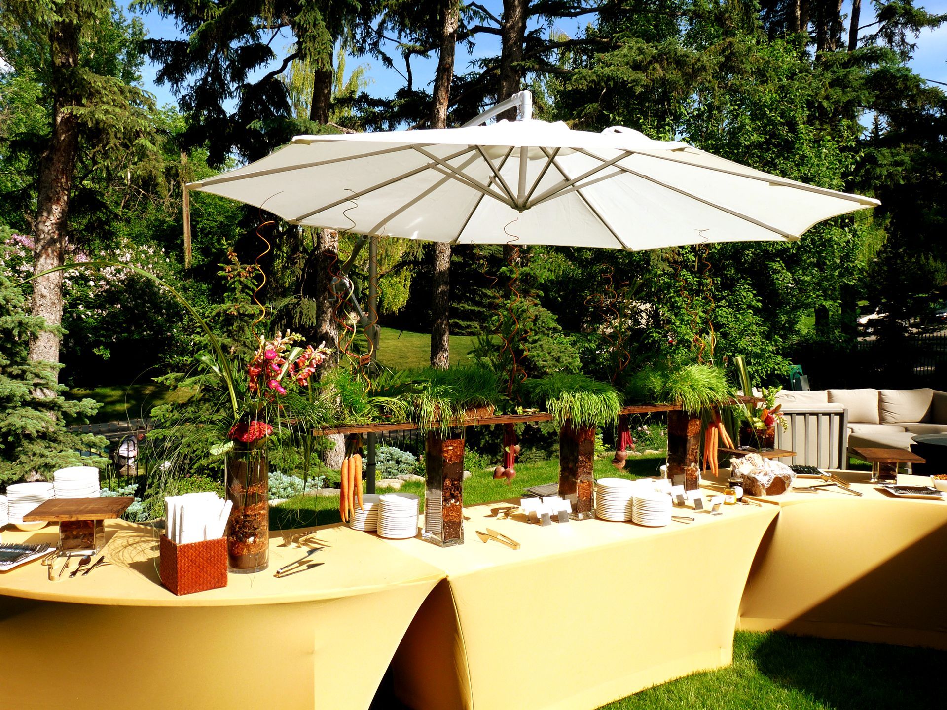 A large white umbrella is hanging over a buffet table