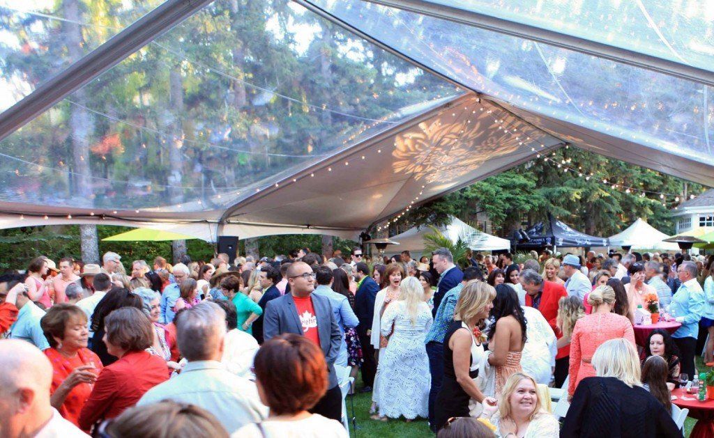 A large group of people are gathered under a clear tent.