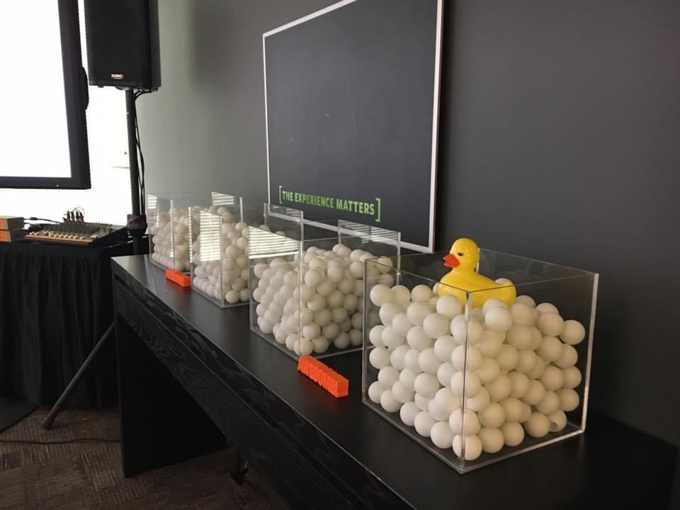 A row of containers filled with golf balls and a yellow rubber duck.