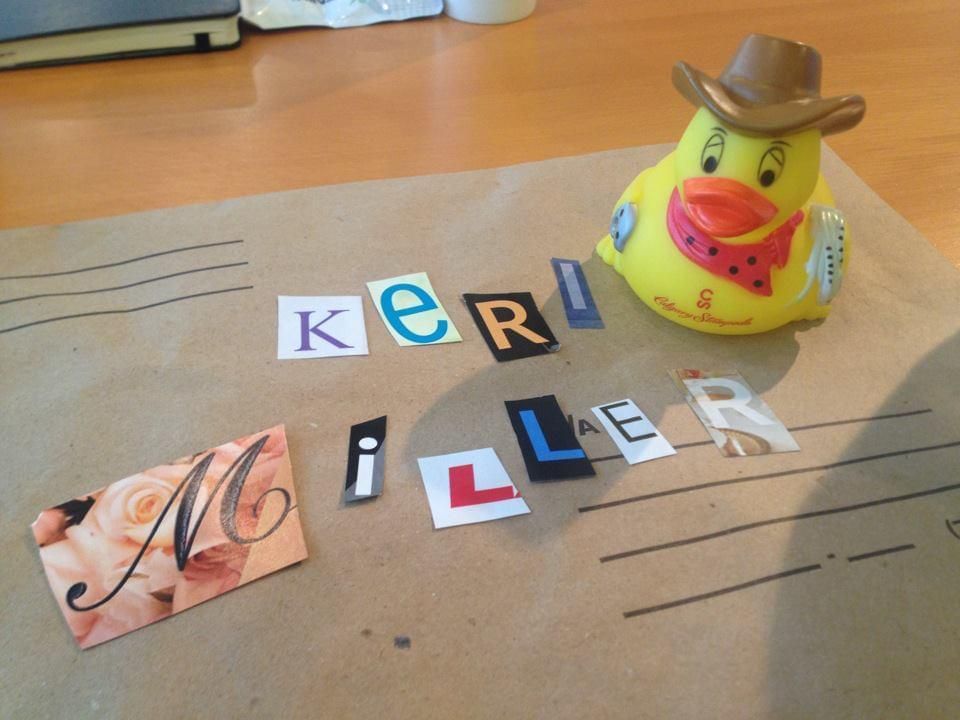 A yellow rubber duck wearing a cowboy hat sits on a piece of paper that says keri miller