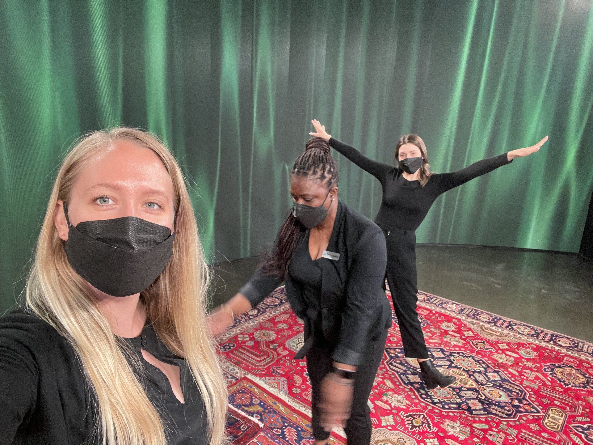 Three women wearing face masks are standing on a stage.