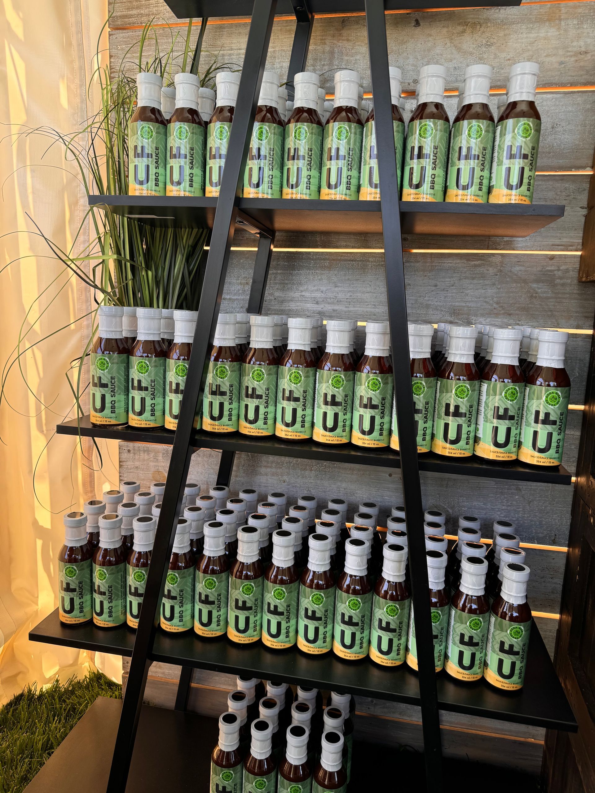 Bottles of product with green label are on shelves of a black metal display.