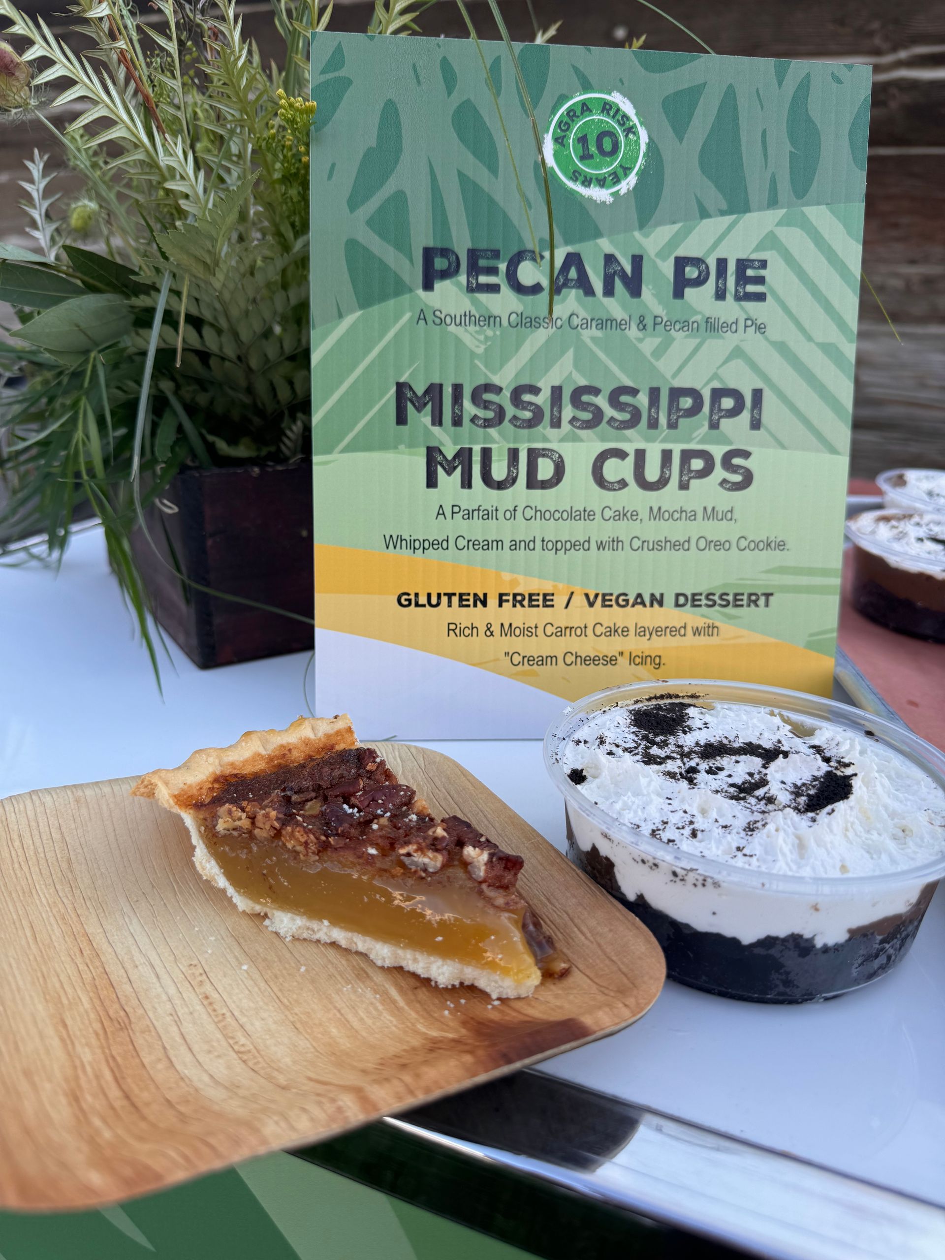 Pecan pie slice and Mississippi mud cup desserts displayed next to a sign.