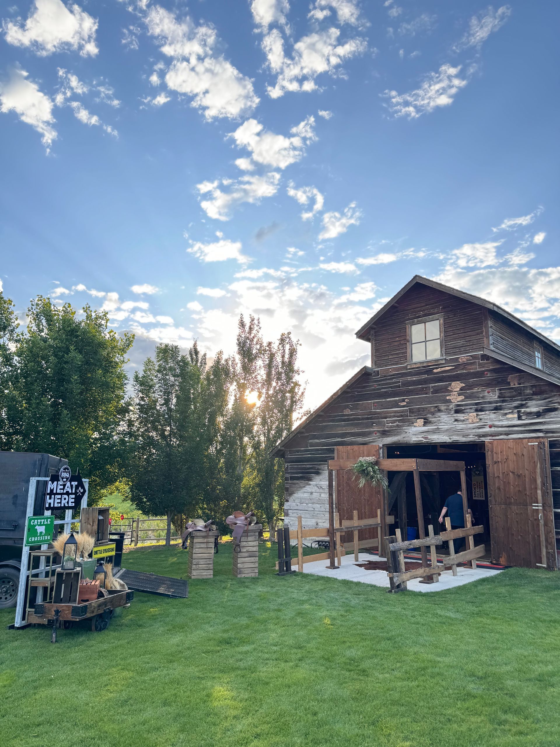 Barn with wooden exterior and open doors, lawn, and sunny sky.