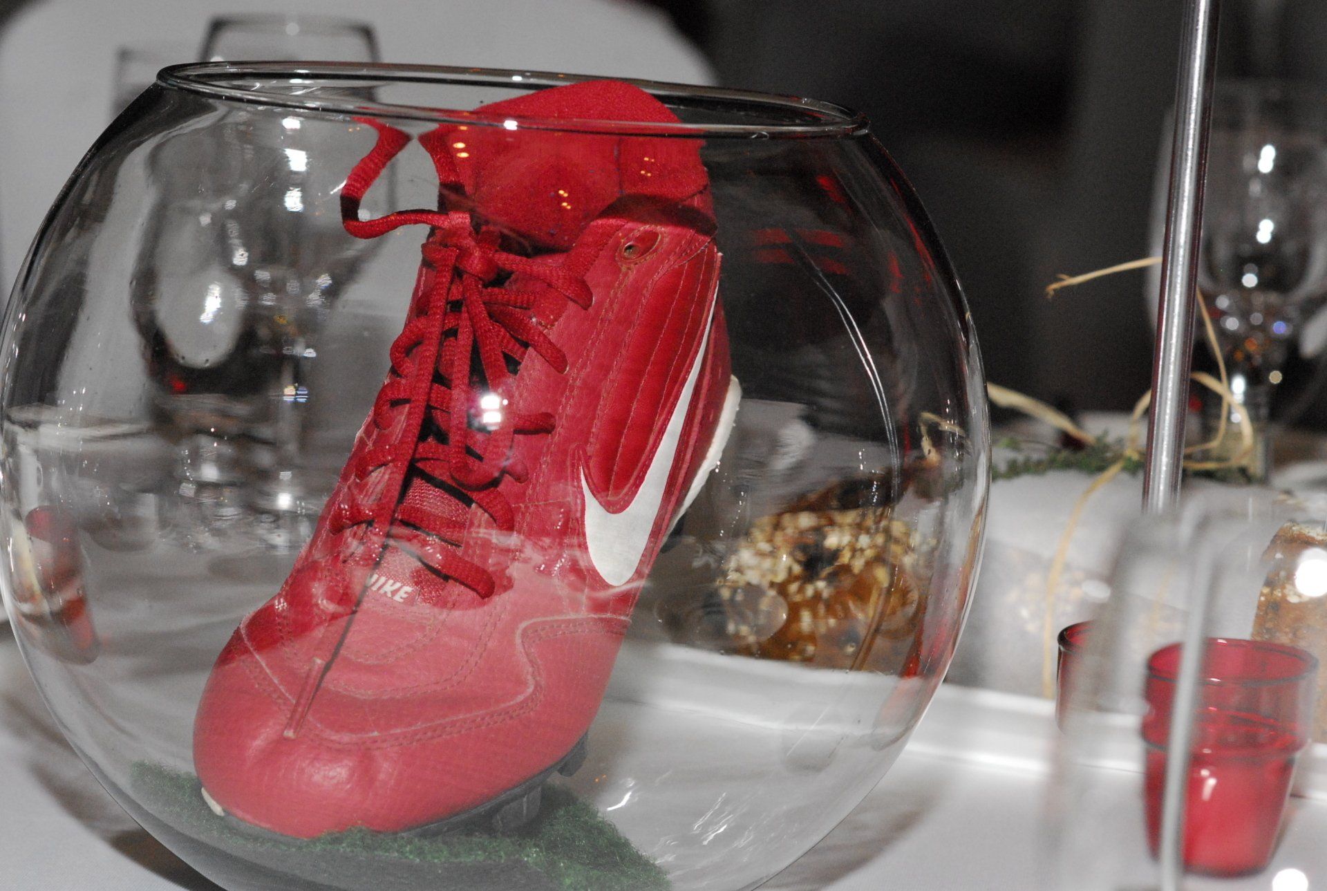 A red nike shoe is in a glass bowl on a table