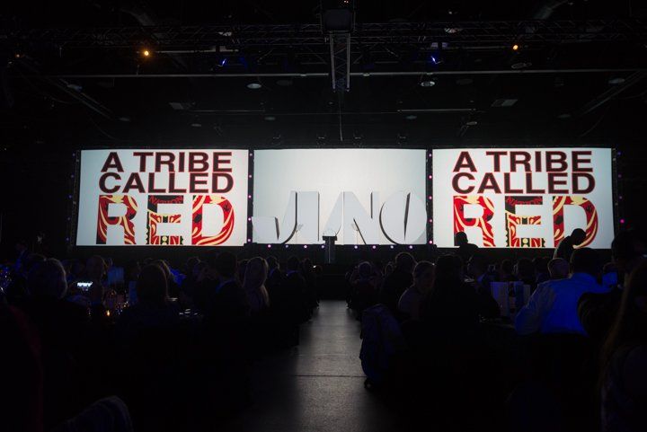 A tribe called red is projected on a large screen in a dark room.
