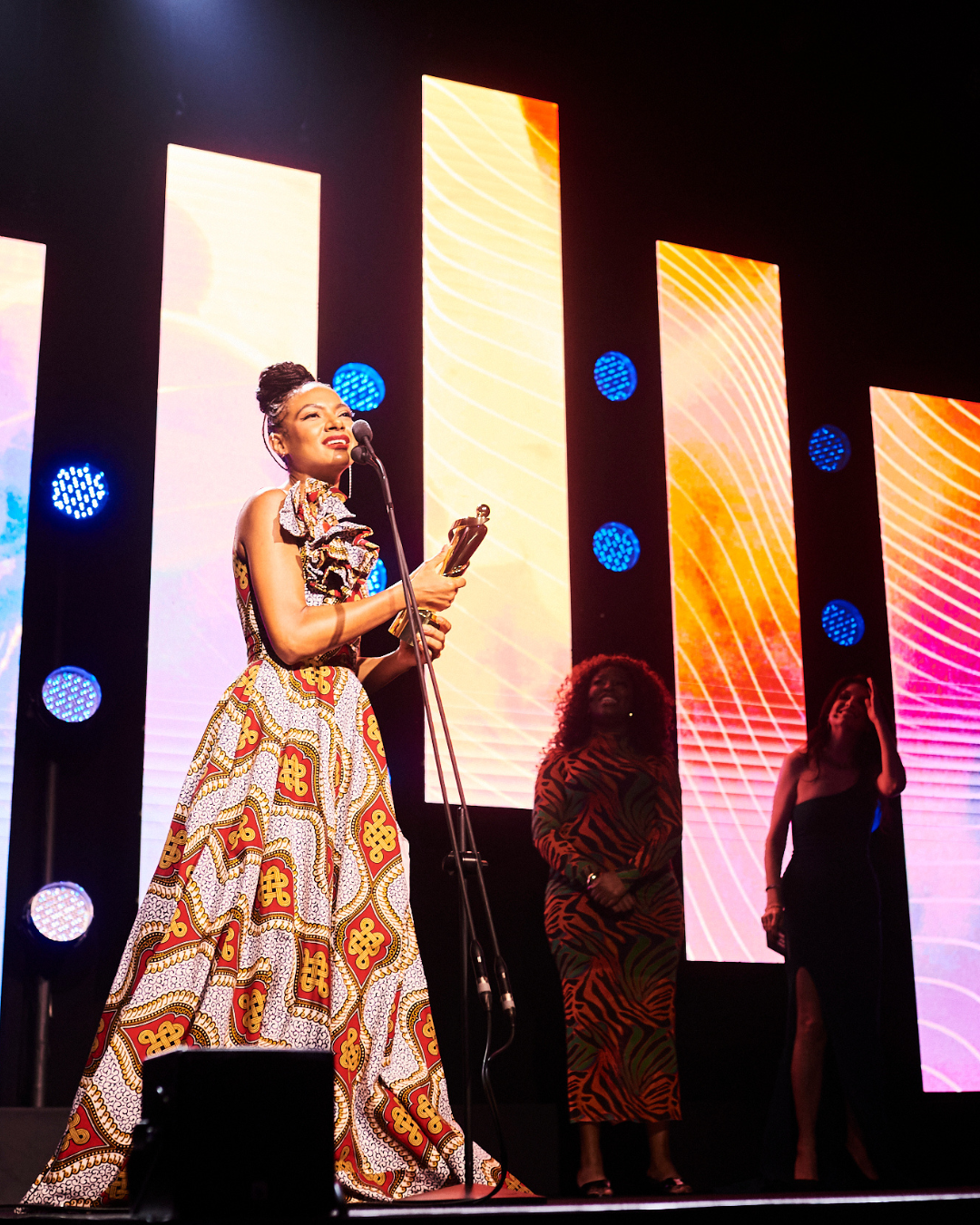 A woman in a long dress is singing into a microphone on a stage