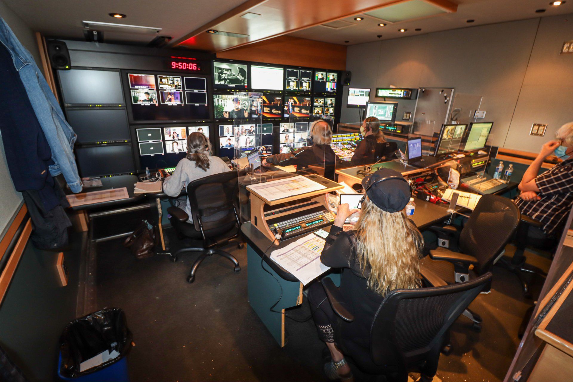 A group of people are sitting at desks in a control room.