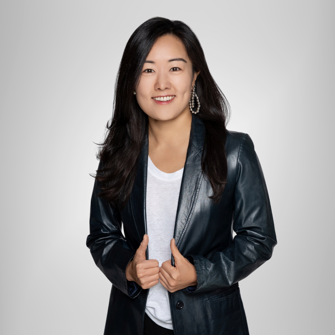 A woman is wearing a black leather jacket and a white shirt.