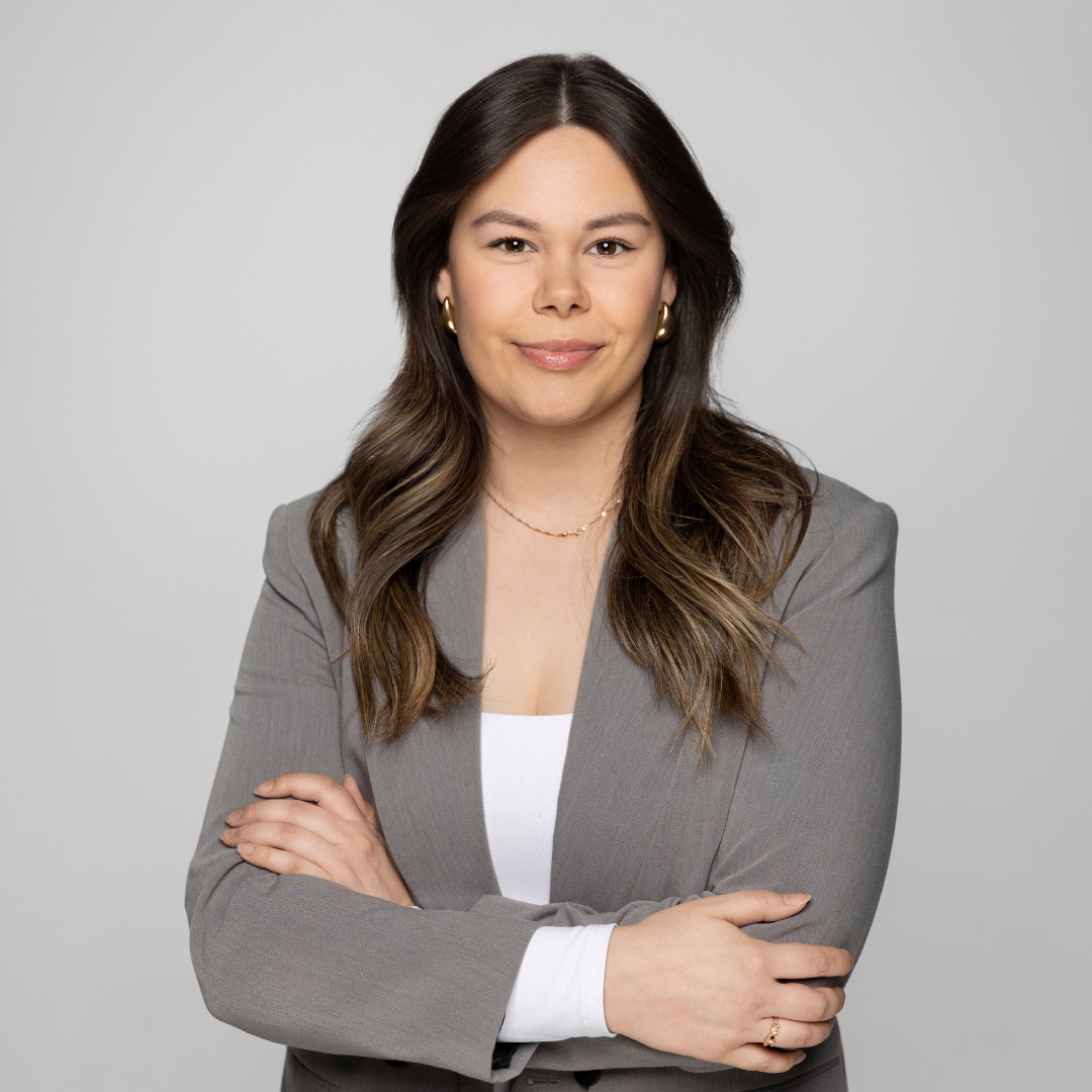 A woman in a gray suit is standing with her arms crossed.