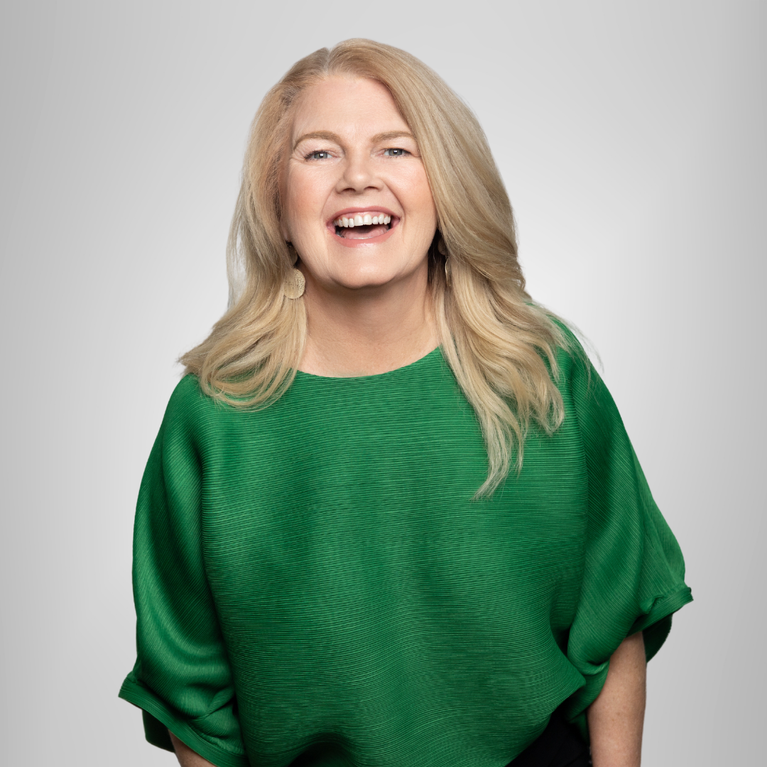 A woman is wearing a green sweater and smiling.