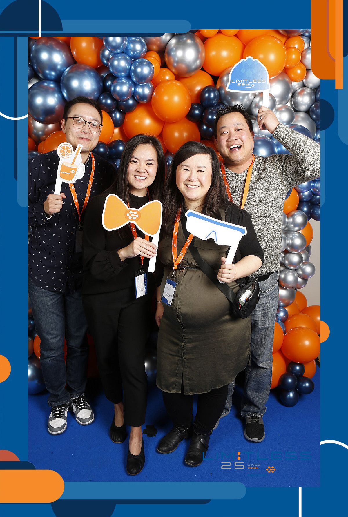 A group of people are posing for a picture in front of a wall of balloons.
